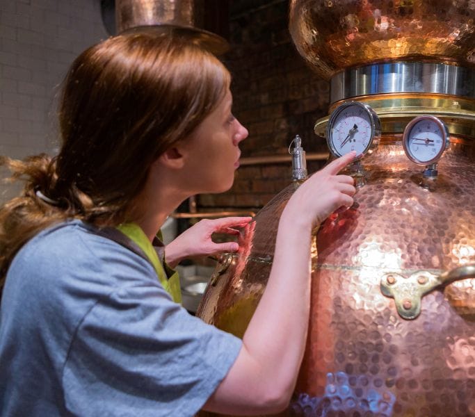 Distillatrice surveillant son alambic à alcool